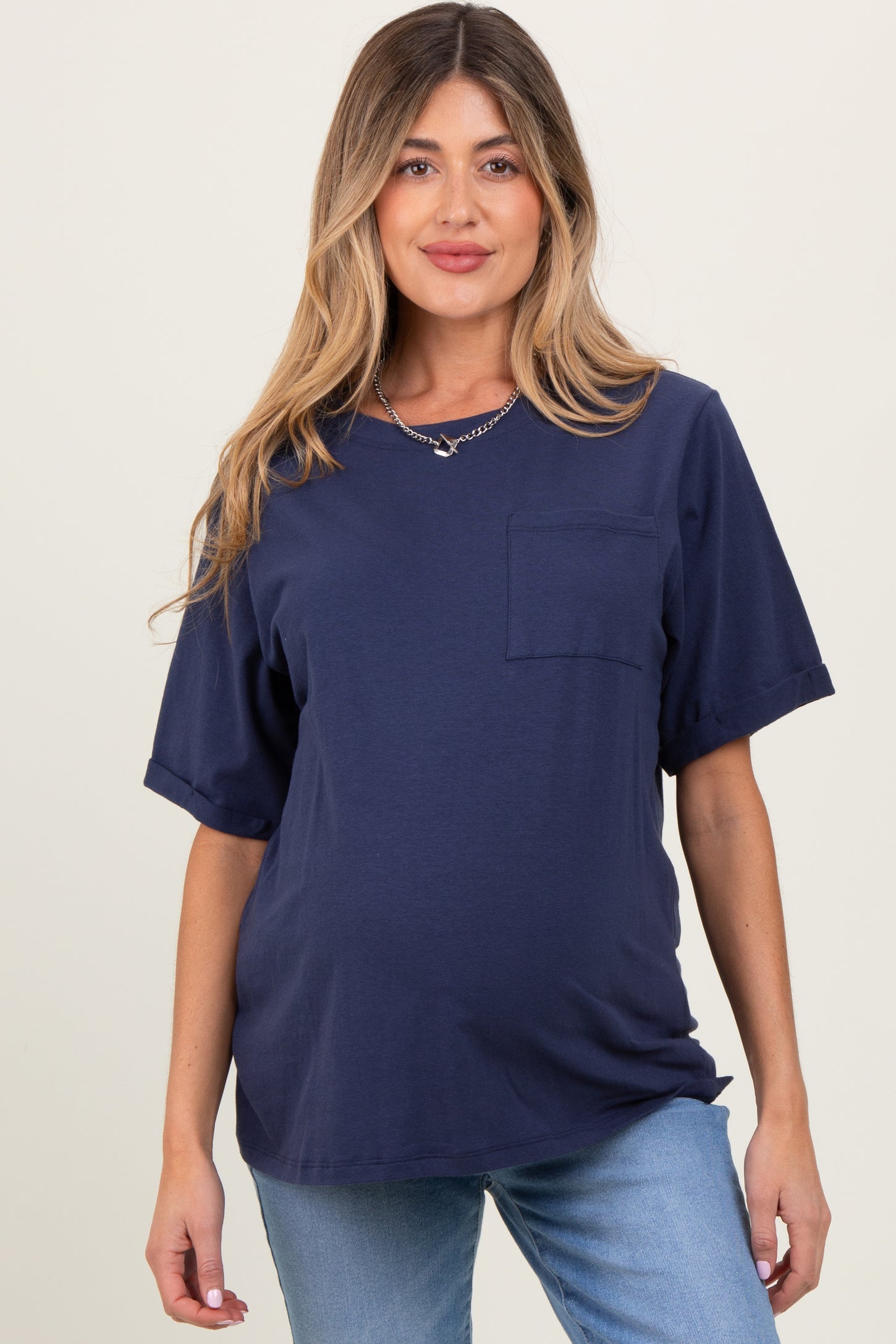 woman wearing a navy blue short sleeve maternity top with a pocket and baby bump visible
