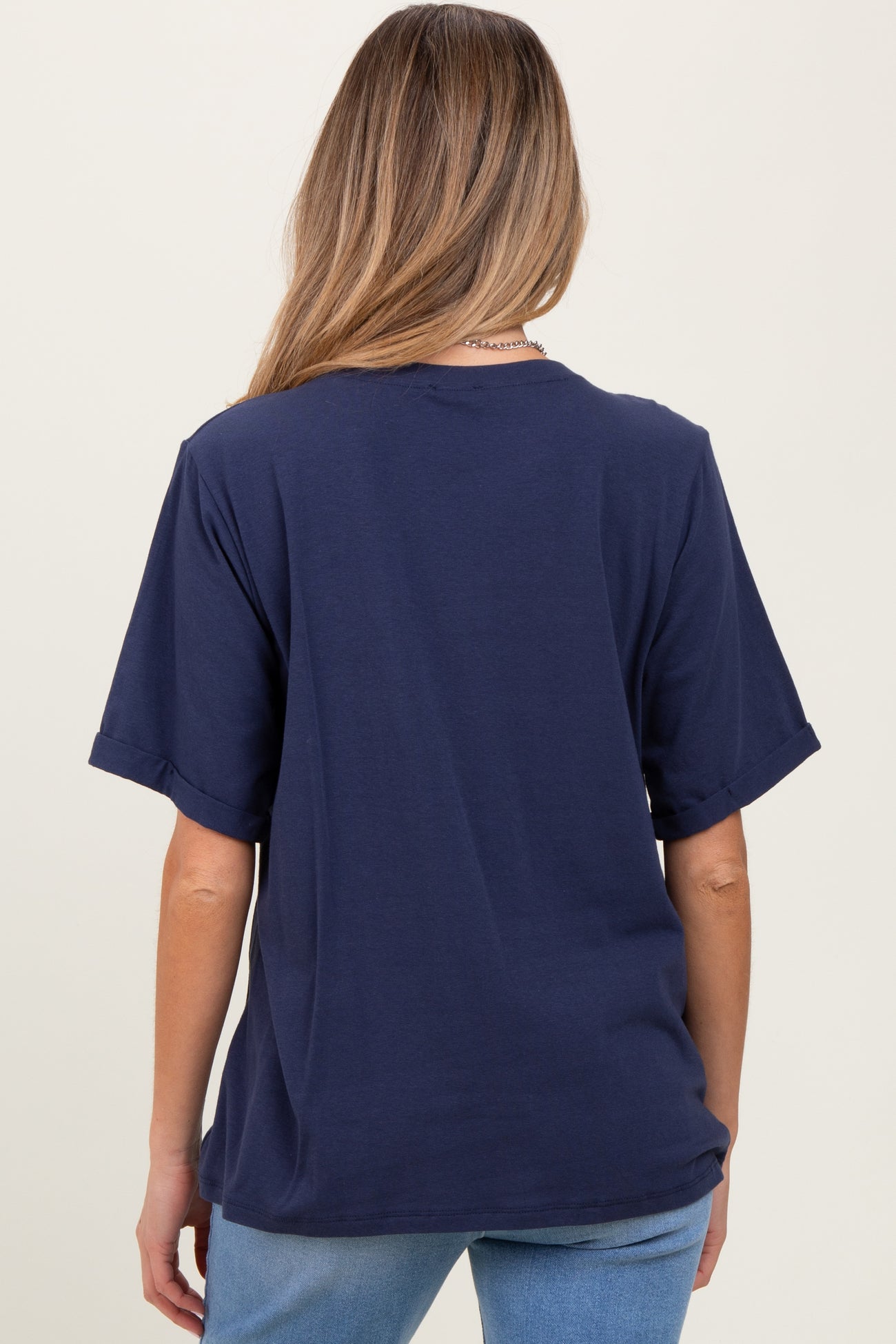woman wearing a navy blue oversized maternity t-shirt, showing the back view, paired with light blue jeans