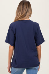woman wearing a navy blue oversized maternity t-shirt, showing the back view, paired with light blue jeans