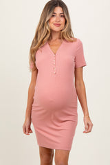 woman wearing a pink short sleeve maternity dress with button details and a visible baby bump