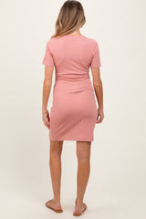 woman wearing a fitted blush pink short sleeve maternity dress, showing a silhouette from the back