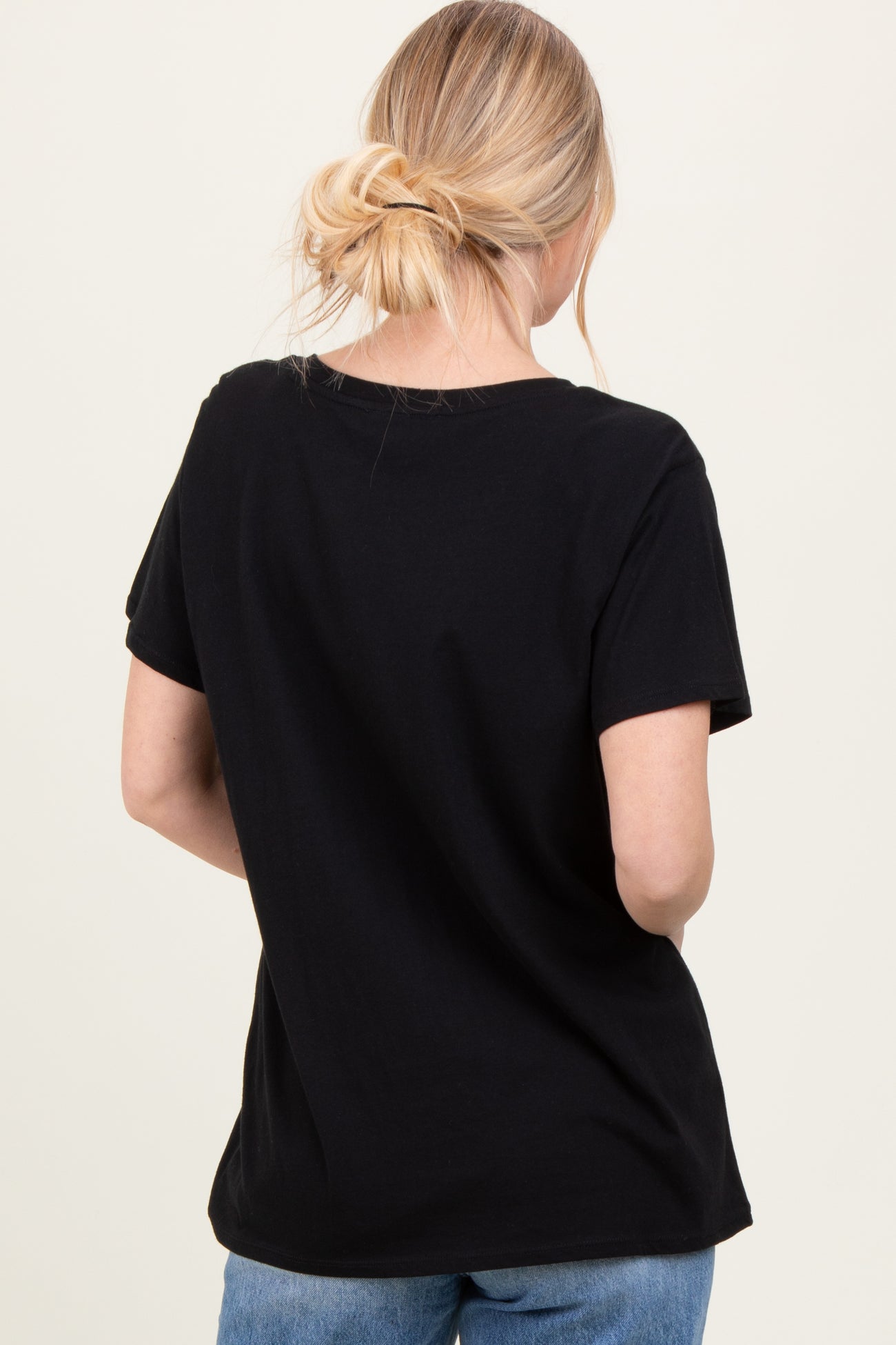 woman wearing a black short sleeve t-shirt, seen from the back, paired with casual blue jeans