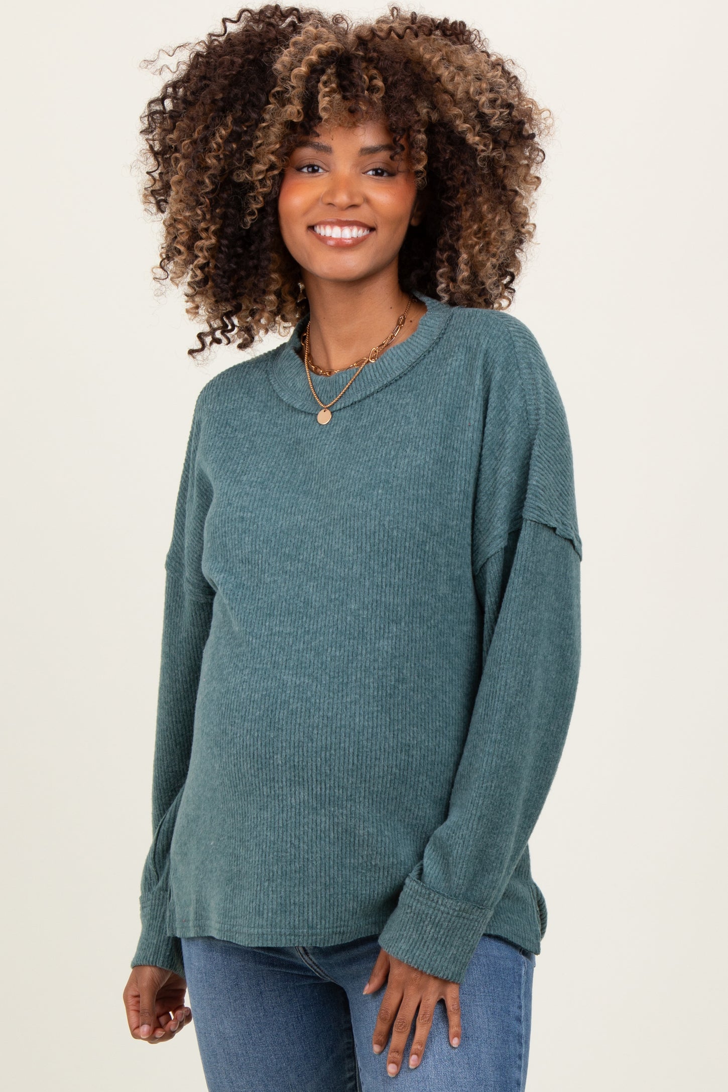 woman wearing a teal ribbed maternity sweater with long sleeves and a relaxed fit, showing her baby bump