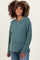 woman wearing a teal ribbed maternity sweater with long sleeves and a relaxed fit, showing her baby bump