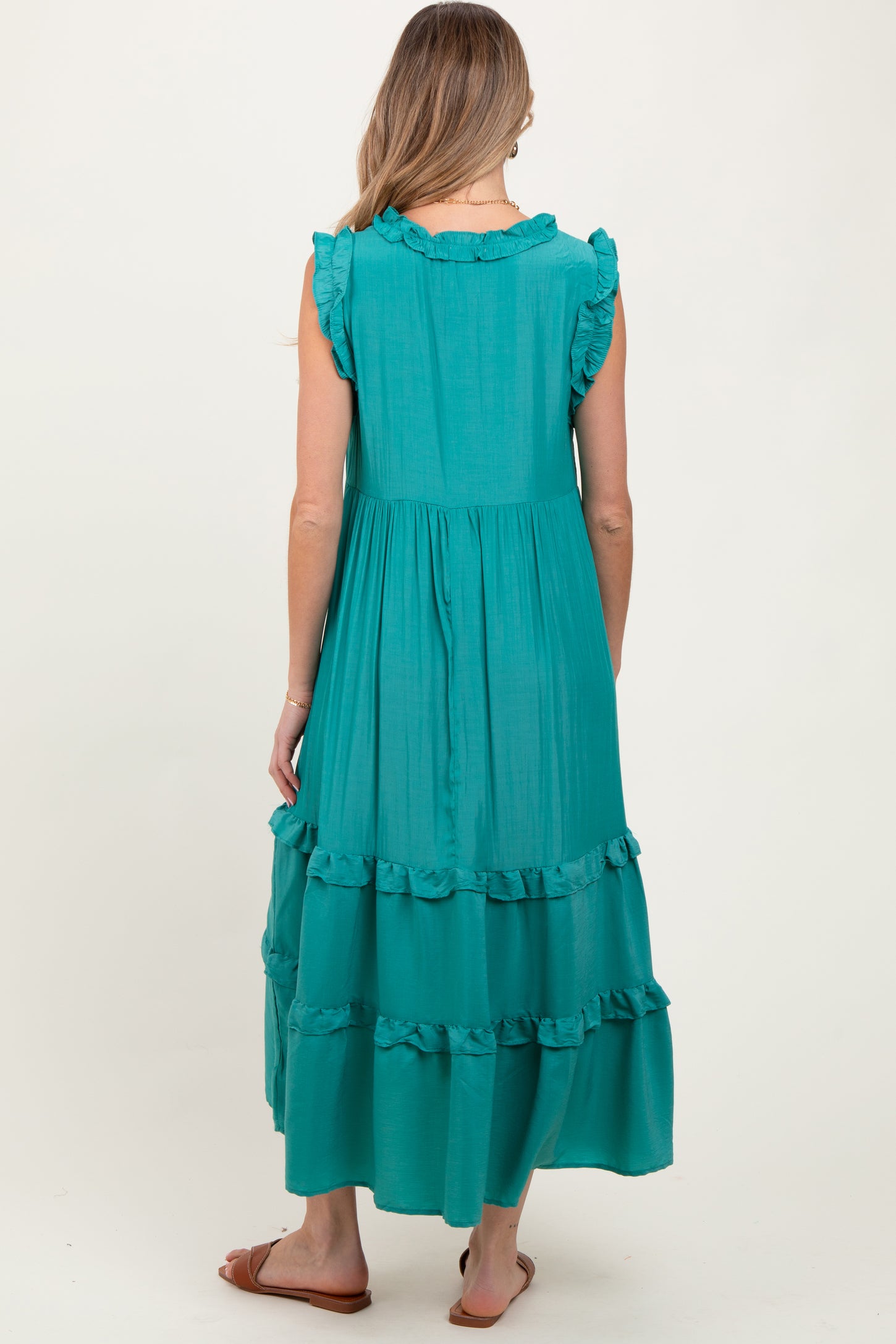 woman wearing a teal sleeveless maternity maxi dress with ruffle details and a tiered skirt, seen from the back