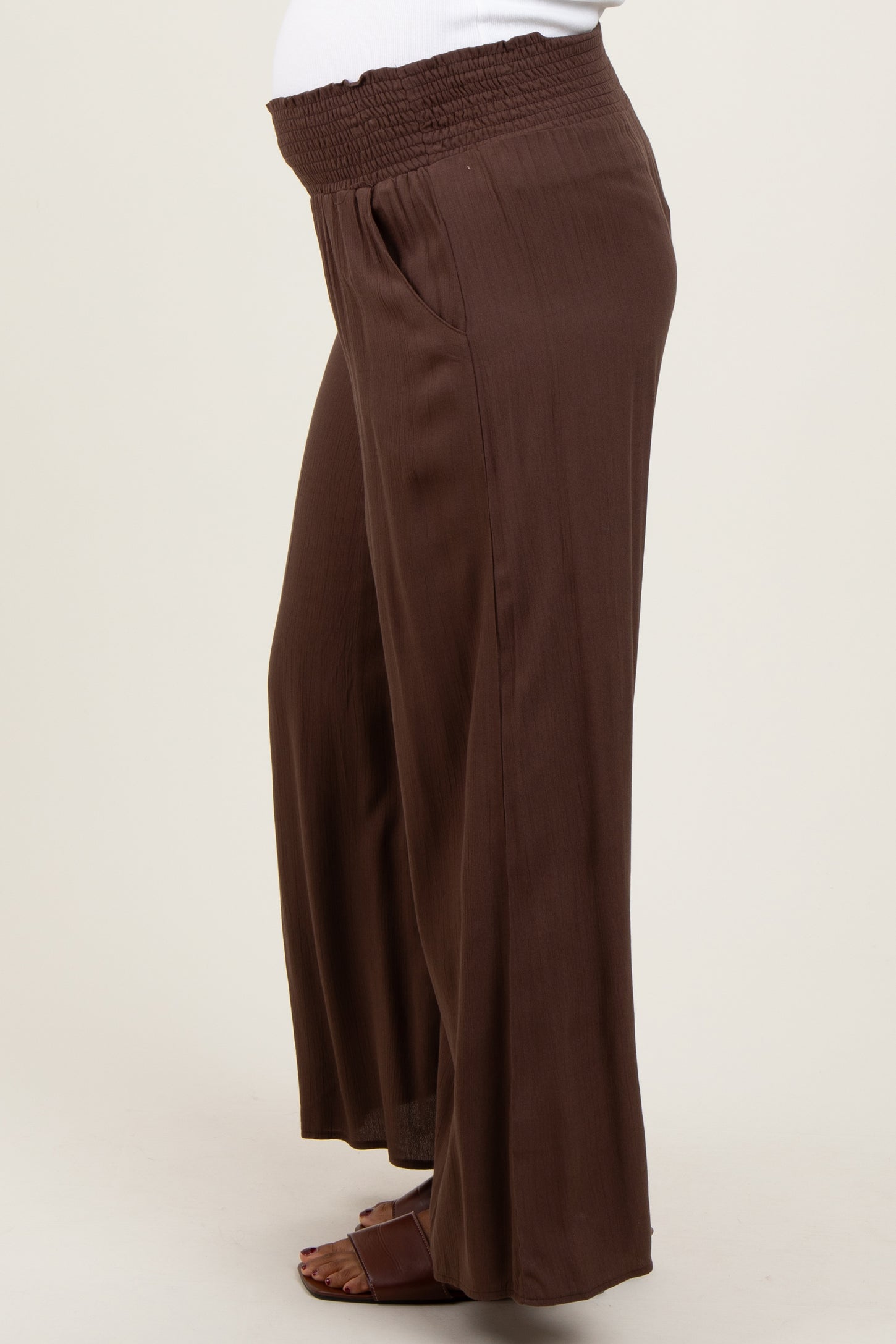woman wearing brown maternity wide leg pants with a smocked waistband and a visible baby bump
