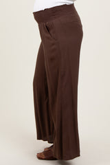 woman wearing brown maternity wide leg pants with a smocked waistband and a visible baby bump