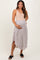 woman wearing a beige maternity dress with a printed skirt and holding her baby bump