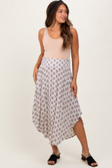woman wearing a blush sleeveless top and a patterned maternity maxi skirt, styled with black slip-on shoes