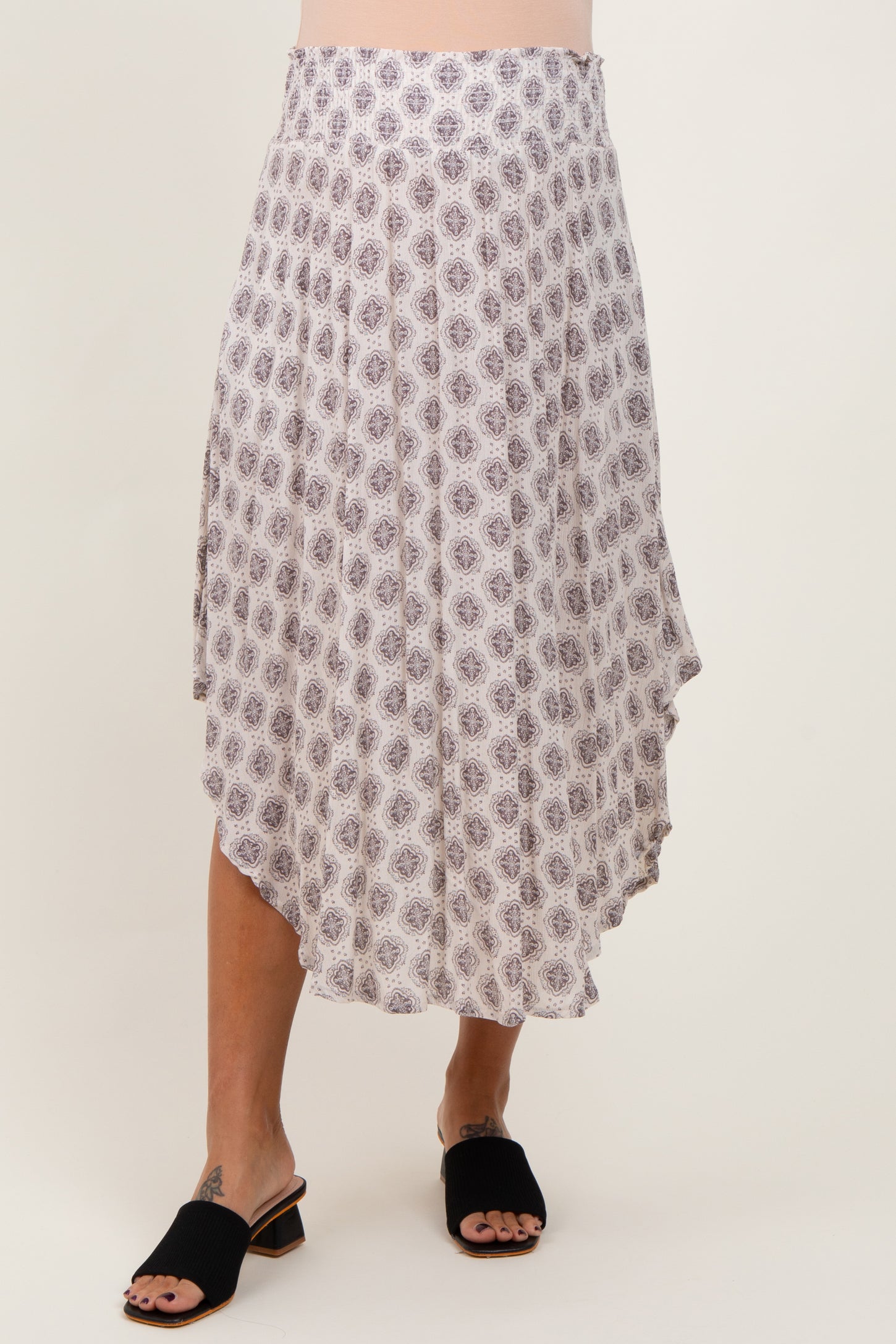 woman wearing a flowy white maternity skirt with a purple floral pattern and an asymmetrical hemline