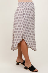 woman wearing a patterned light purple maternity skirt with a high-low hem and stylish slide sandals