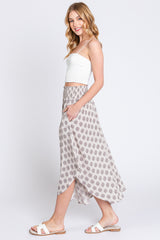 woman wearing a white cropped tank top and a flowy patterned maxi skirt with a side slit