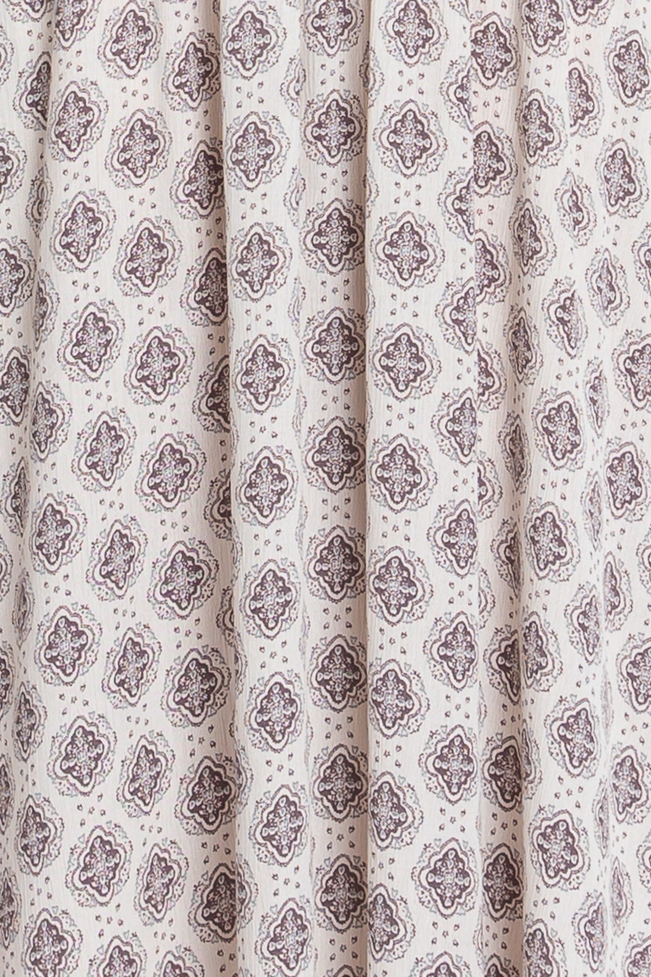 white fabric featuring a brown floral and geometric print with pleats