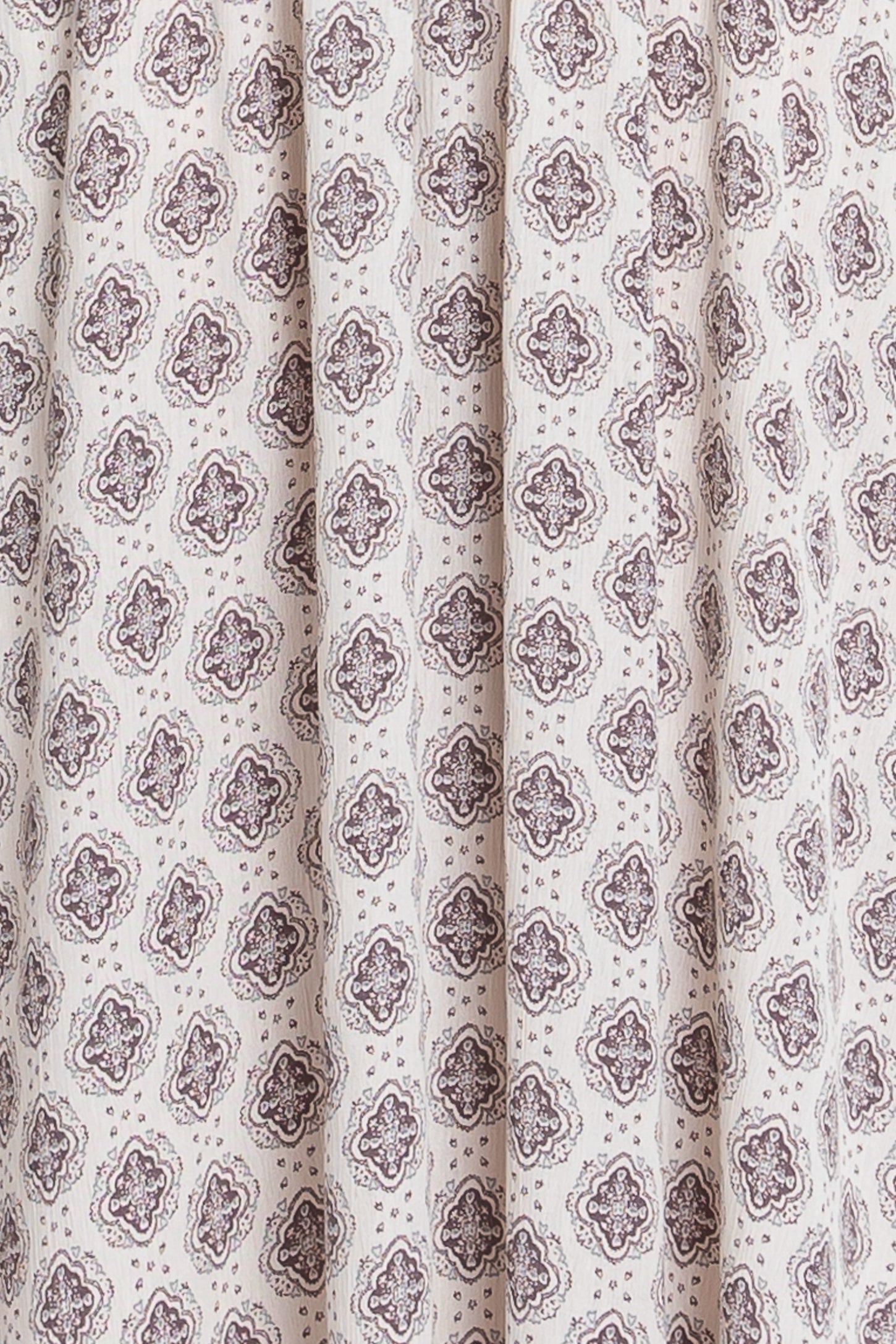 white fabric featuring a brown floral and geometric print with pleats