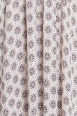 white fabric featuring a brown floral and geometric print with pleats