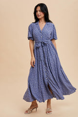 woman wearing a floral print blue maxi dress with short sleeves and a tie-waist detail