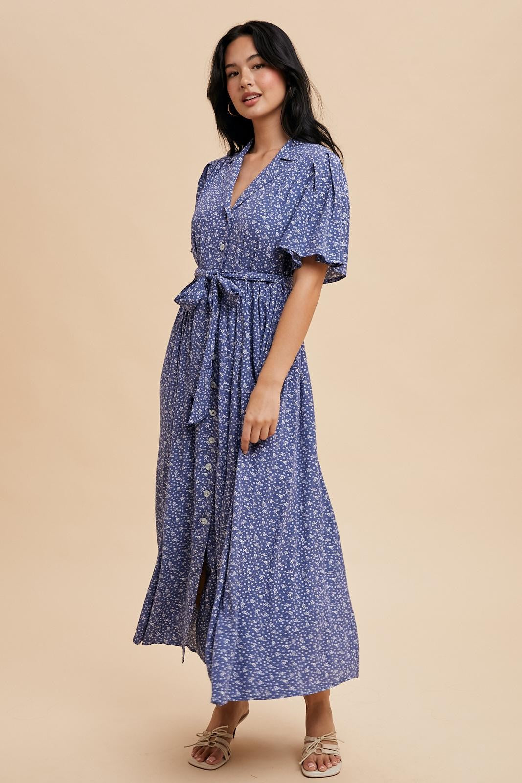 woman wearing a floral chiffon maxi dress in blue with short sleeves and a tied waist