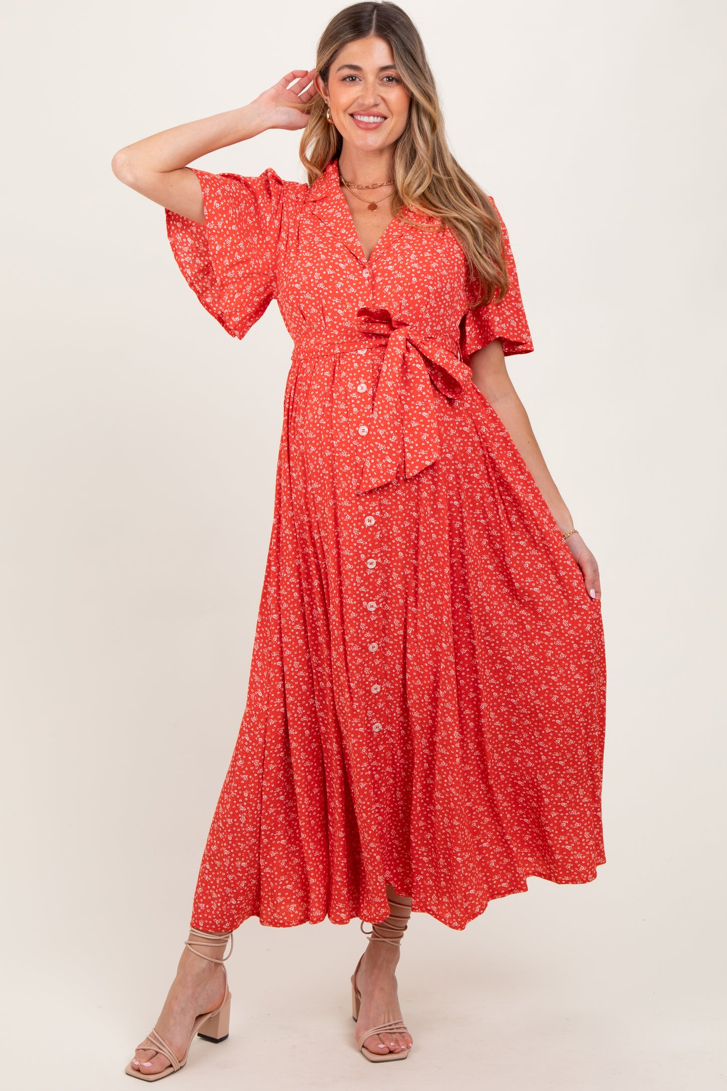 woman wearing a red floral maternity maxi dress with short flutter sleeves and a wrap tie detail