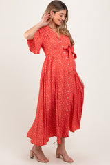 woman wearing a red floral maternity maxi dress with a tie waist and button details, showcasing her baby bump