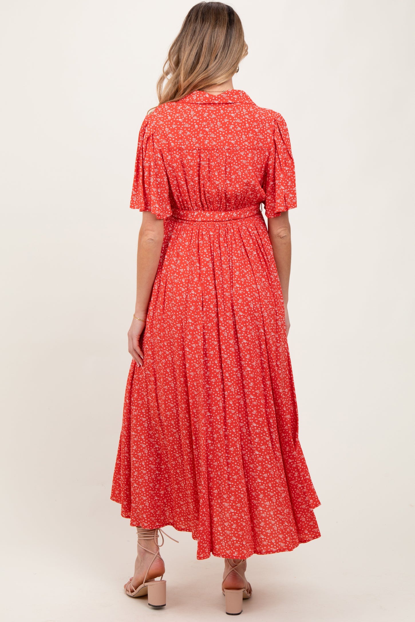 woman wearing a red floral print maternity dress with short sleeves and a tie waist, shown from the back