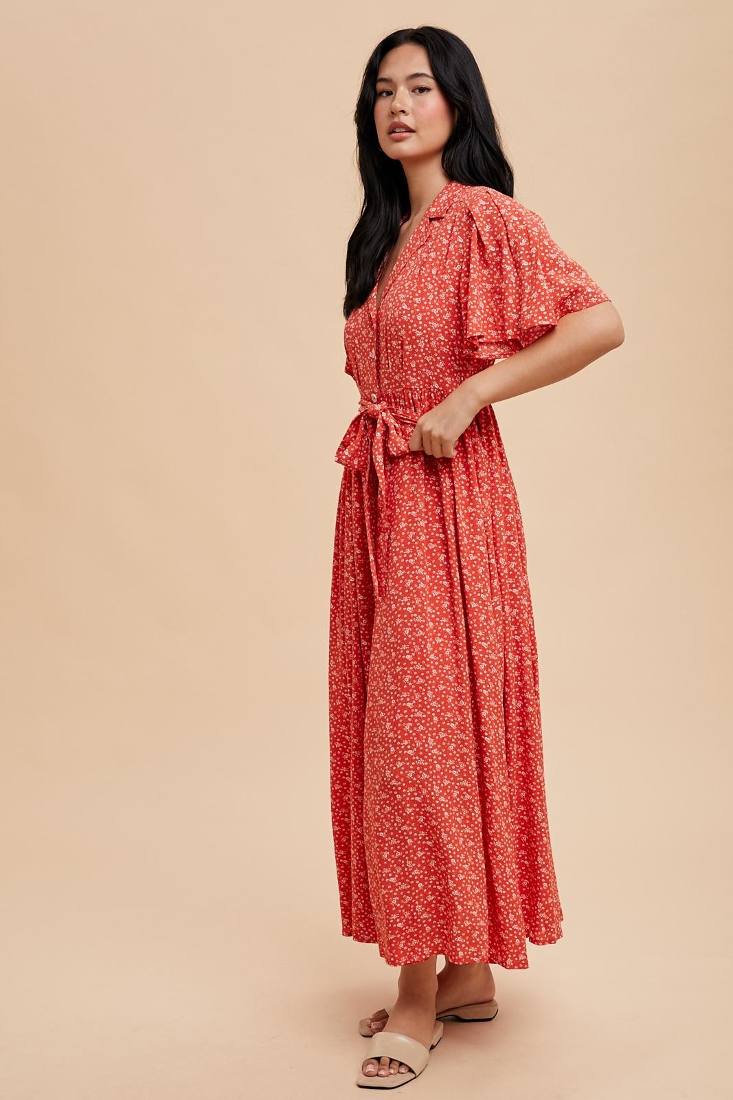woman wearing a red floral maxi dress with short puff sleeves and a tie waist detail