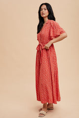 woman wearing a red floral maxi dress with short puff sleeves and a tie waist detail