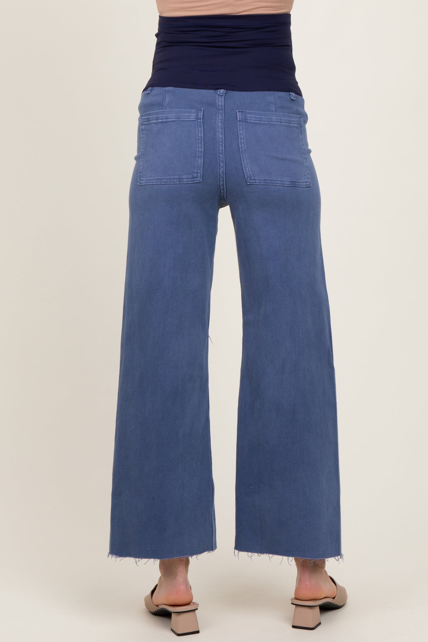 woman wearing a pair of light blue maternity wide-leg jeans with a high waist and raw hem detail from the back