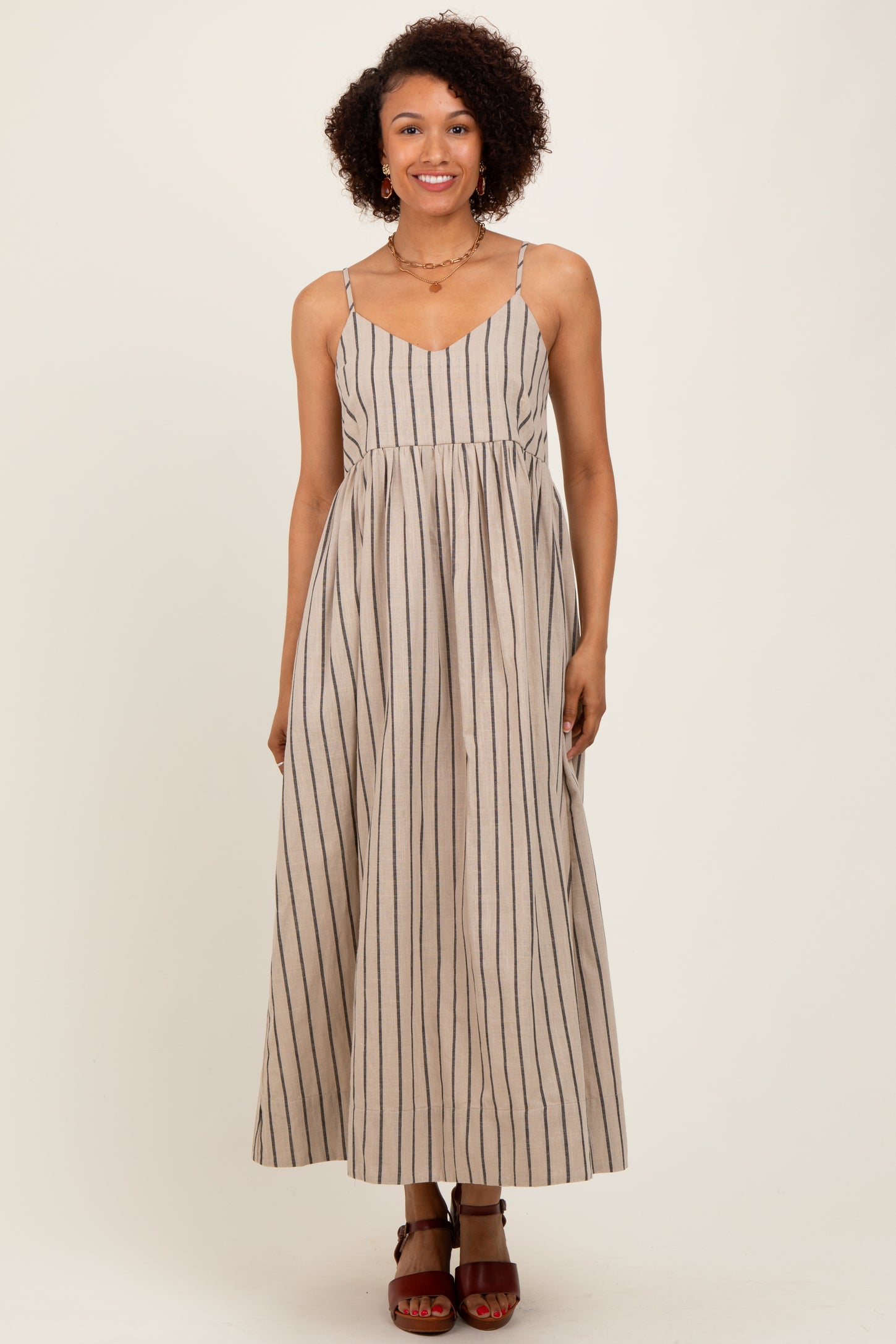 woman wearing a beige and navy striped maxi dress with adjustable straps and a flowy silhouette