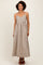 woman wearing a beige and navy striped maxi dress with adjustable straps and a flowy silhouette