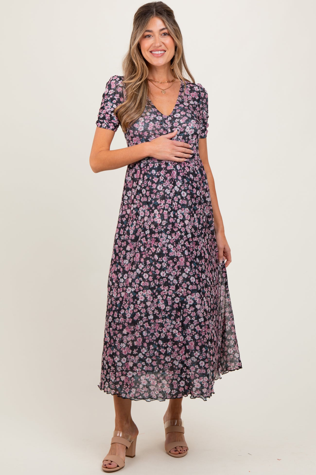 woman wearing a floral black maternity dress with short sleeves and a v-neck, holding her baby bump