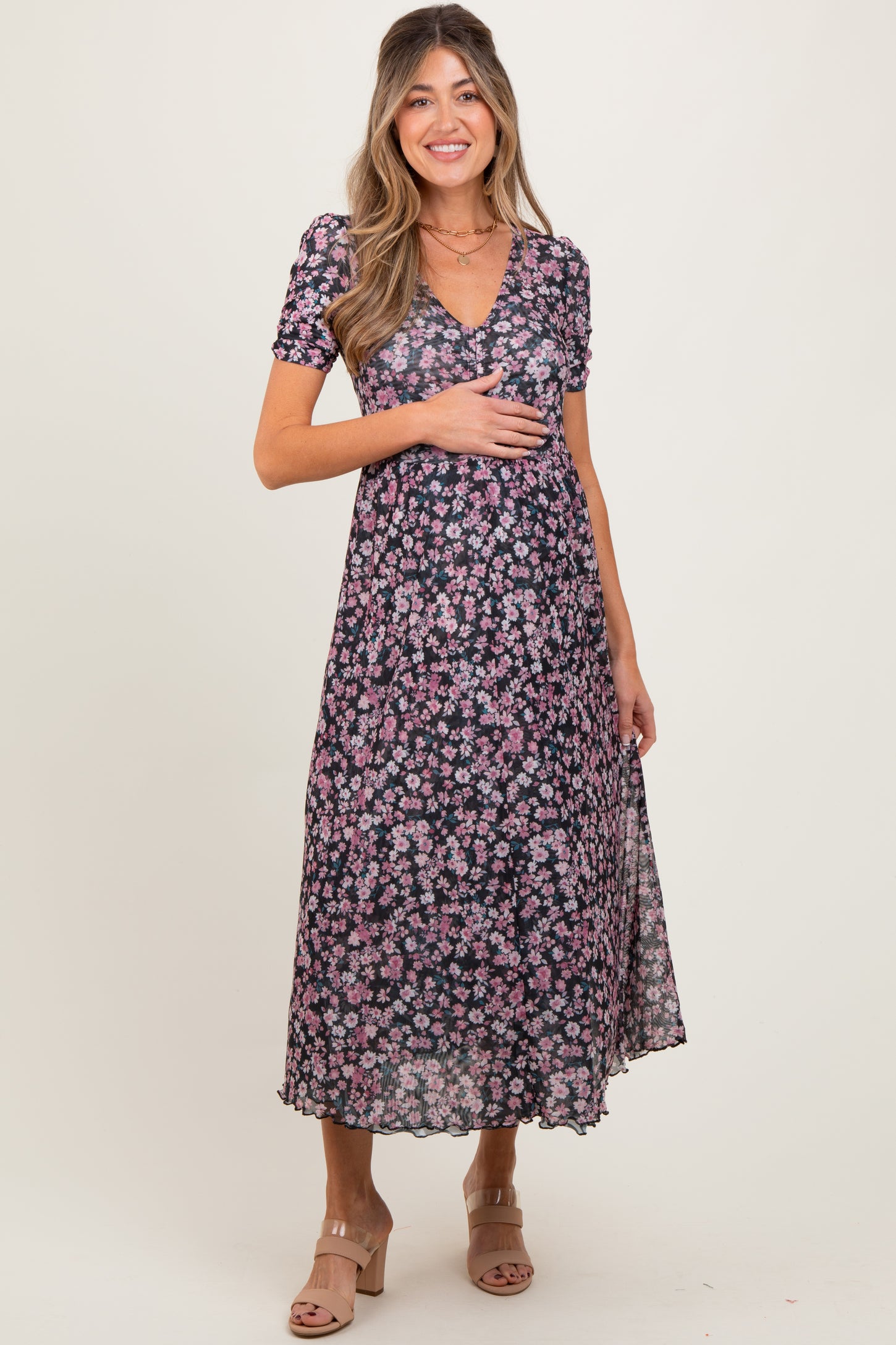 woman wearing a floral black maternity dress with short sleeves and a v-neck, holding her baby bump