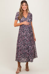 woman wearing a floral black maternity dress with short sleeves and a v-neck, holding her baby bump