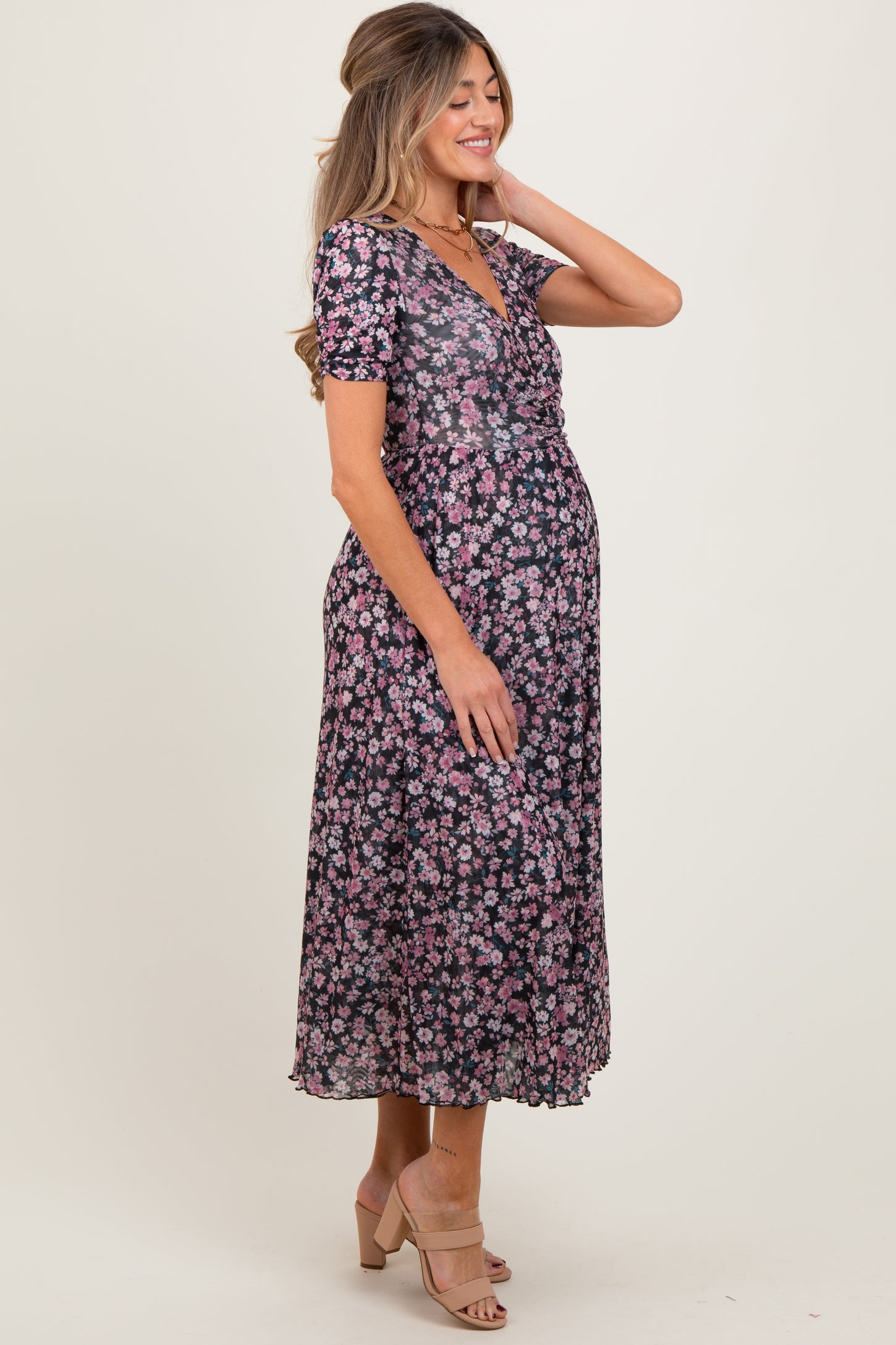 woman wearing a black floral maternity dress with short sleeves and a flowy skirt, showing her baby bump
