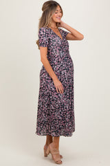 woman wearing a black floral maternity dress with short sleeves and a flowy skirt, showing her baby bump