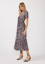 woman wearing a black floral midi dress with short sleeves and a cinched waist, styled with strappy sandals