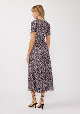 woman wearing a black floral midi dress with short sleeves and a cinched waist, standing with her back to the camera