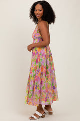 woman wearing a colorful floral maxi dress with a flowy design and spaghetti straps, smiling while standing sideways