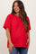 woman wearing a red maternity top with wide sleeves and a loose fit, smiling while showcasing her baby bump