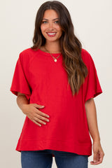 woman wearing a red short sleeve maternity top and holding her baby bump