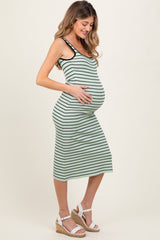 woman wearing a green and black striped maternity dress, smiling and holding her baby bump