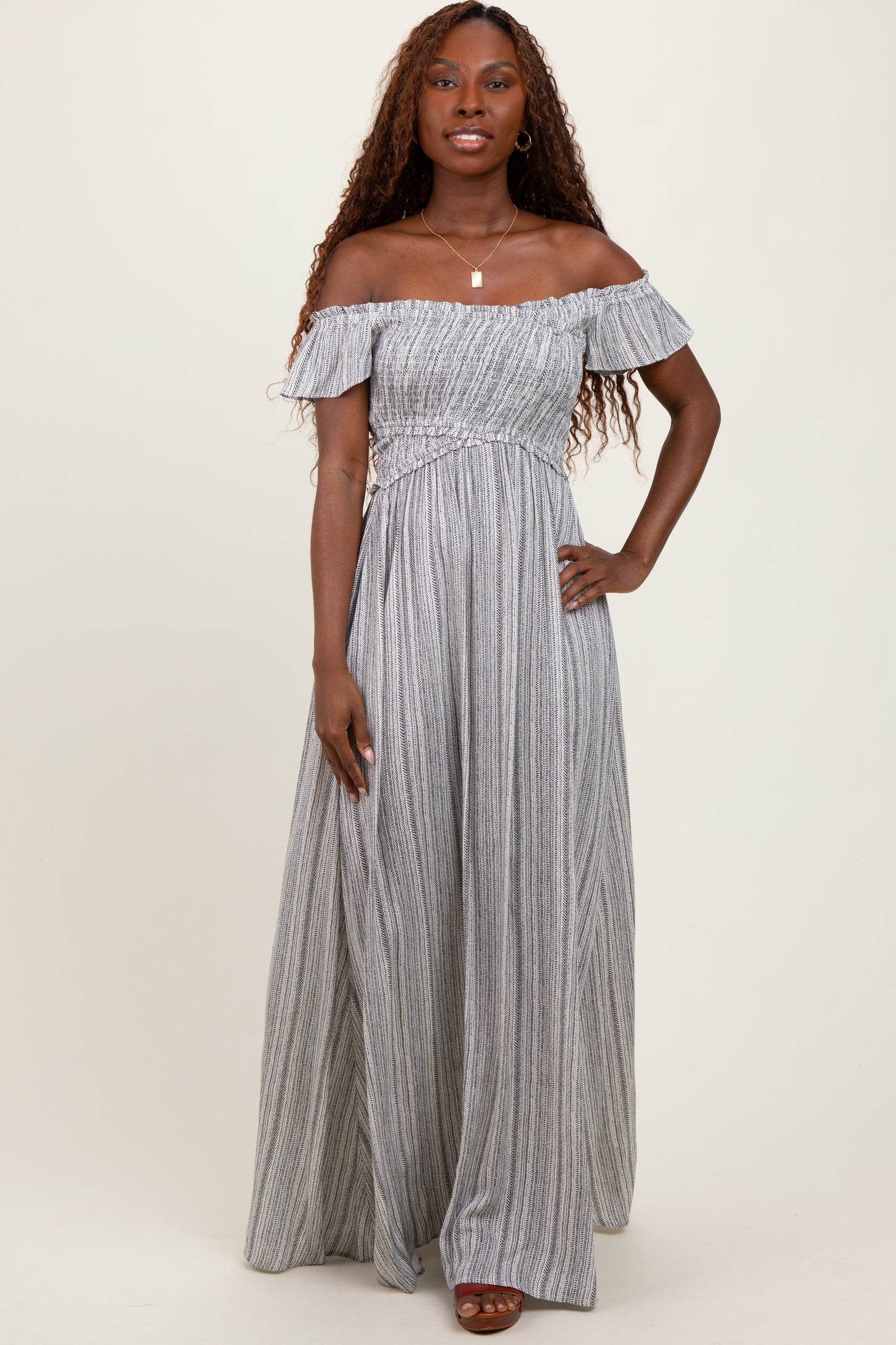 woman wearing a gray and white striped off-the-shoulder maxi dress with a fitted bodice and flowy skirt