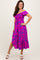 woman wearing a vibrant pink floral off-shoulder midi dress with smocked bodice and ruffled hemline