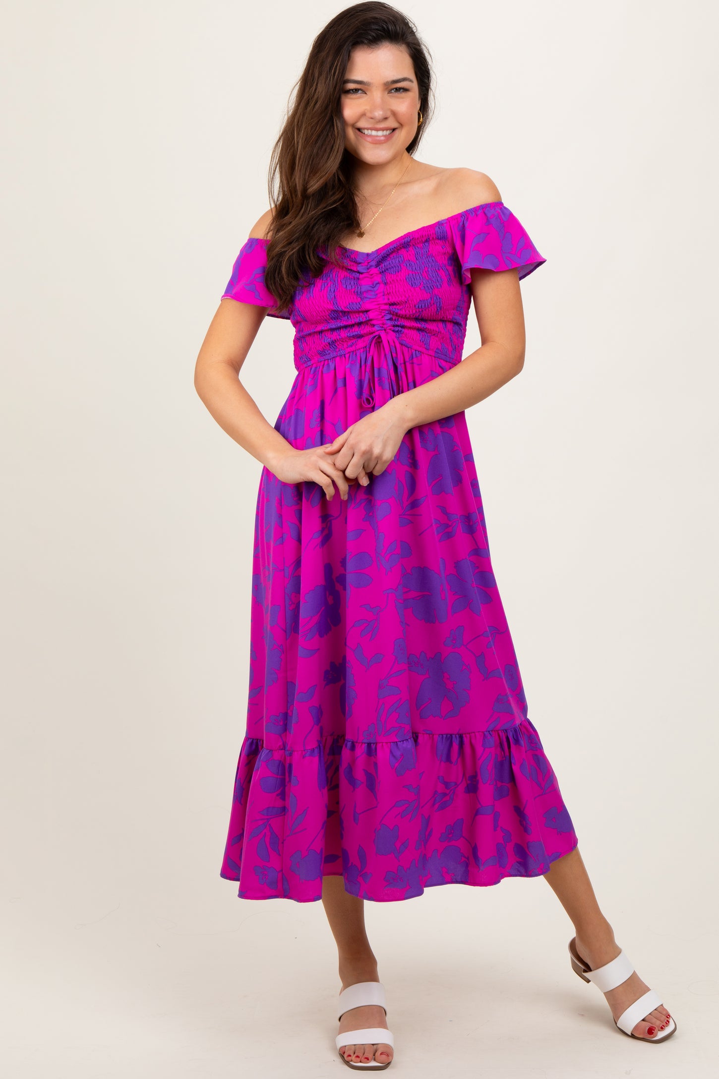 woman wearing a pink off-the-shoulder floral maxi dress with smocking and a ruffled hem