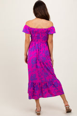 woman wearing a vibrant pink off-the-shoulder maxi dress with floral patterns and a tiered hem, seen from the back