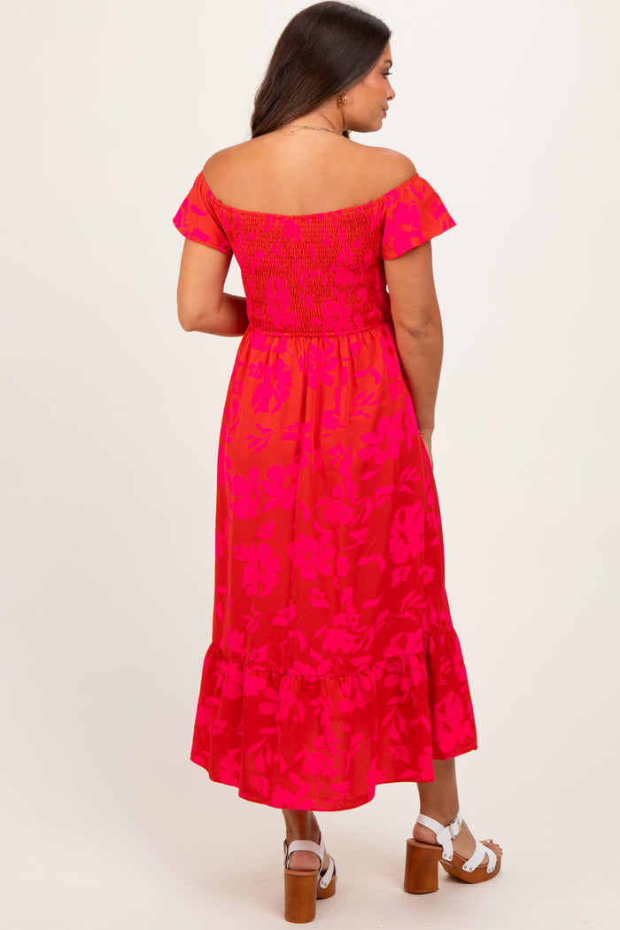 woman wearing a pink floral off-shoulder maternity dress with a smocked bodice and ruffle hem