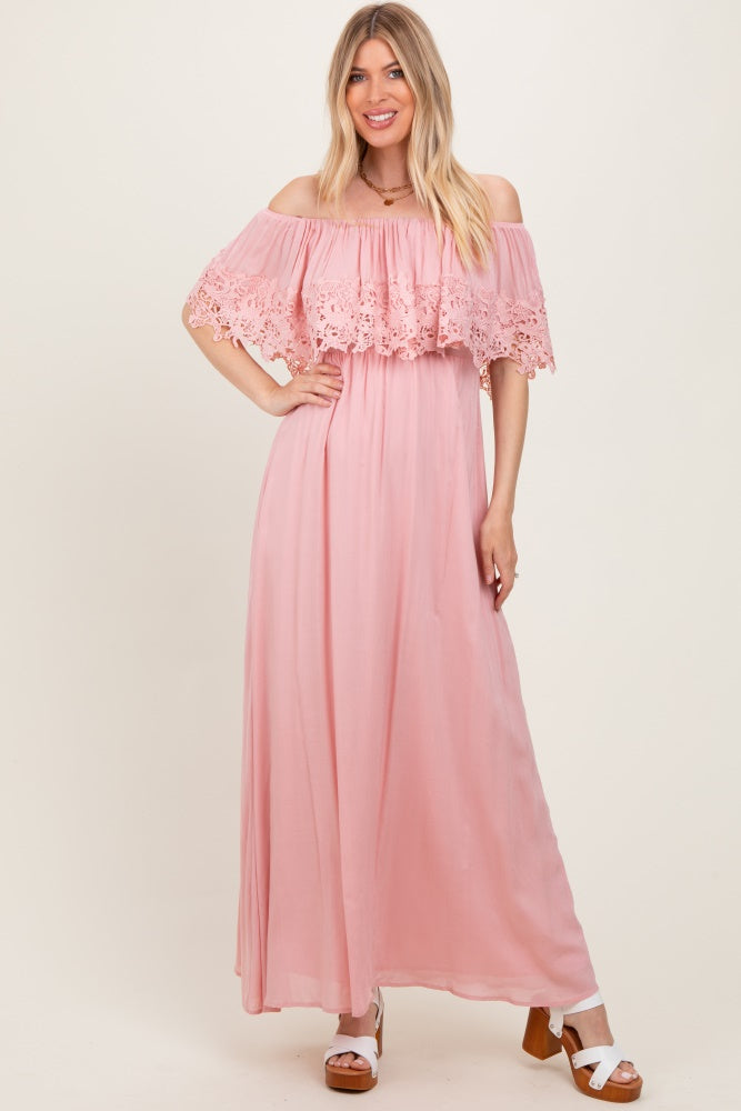 woman wearing a pink off-the-shoulder maxi dress with lace detailing on the bodice and flowy skirt