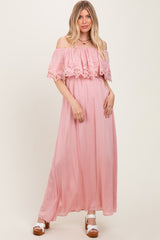 woman wearing a light pink off-the-shoulder maxi dress with lace detailing and a flowy silhouette