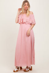woman wearing a pink off-the-shoulder maxi dress with lace details and a flowy silhouette