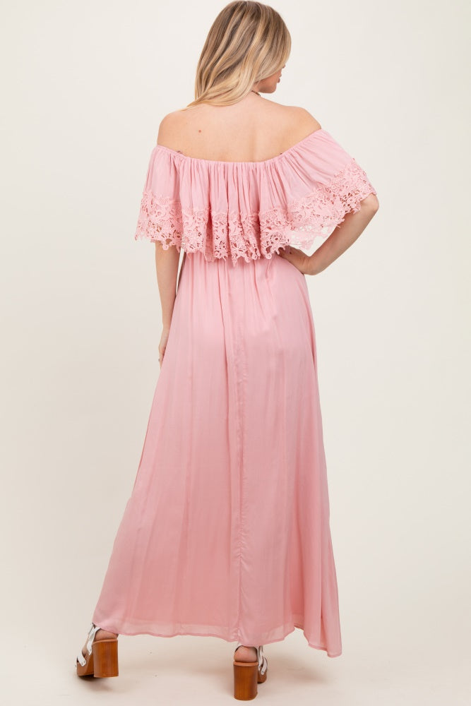 woman wearing a pink off-the-shoulder maxi dress with lace detailing on the sleeves and back