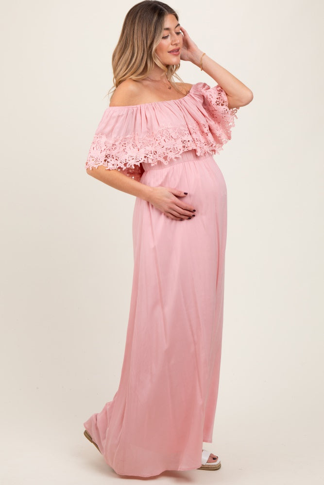 woman wearing a pink off-the-shoulder maternity gown with lace detail and a visible baby bump
